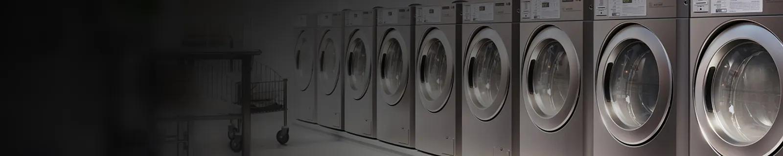Row of LG commercial front-load washing machines lined up in a commercial laundry facility.