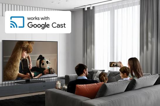 Family watching TV in a modern living room with a "works with Google Cast" sign on the wall.

Transcribed Text:

works with Google Cast