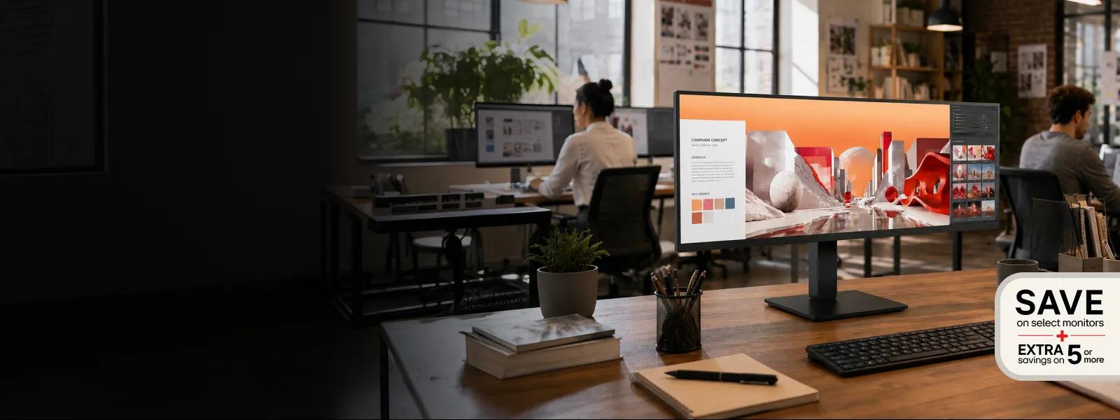 LG FHD Monitor displaying creative content sitting on desk in office setting with a Save on select monitors and Extra savings on 5 or more badge