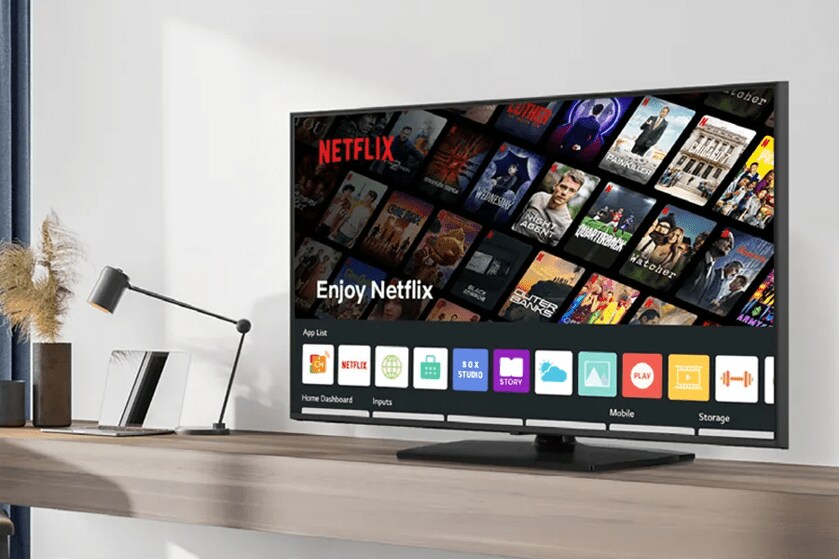 A TV on a wooden surface showing a Netflix interface with app icons at the bottom.