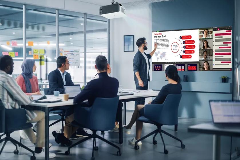 Professionals in a meeting room look at the business presentation displayed by an LG projector.