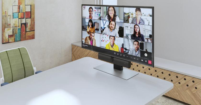 A video conference call displayed on a monitor in a modern office setting.