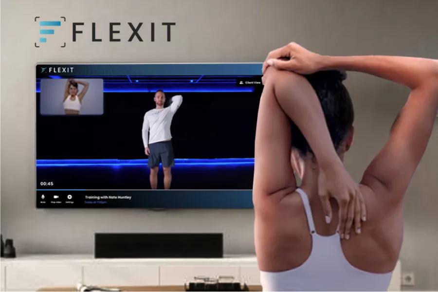 A woman stretches while watching exercise content on her TV.