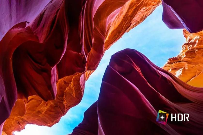 View of Antelope Canyon with colorful rock formations and a blue sky above.