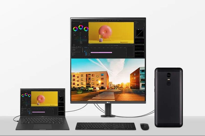 Workspace with a laptop, vertical monitor, and smartphone on a desk.