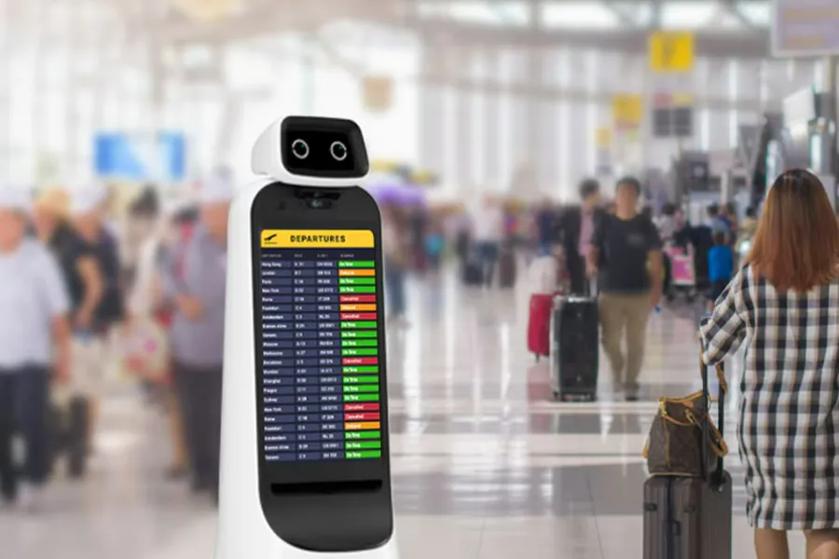 CLOi stands in a busy airport terminal, with a Departures list displayed on her screen.