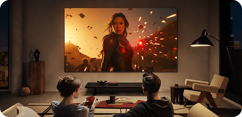 Couple in modern living room watching an action scene with vivid special effects on a large LG TV.