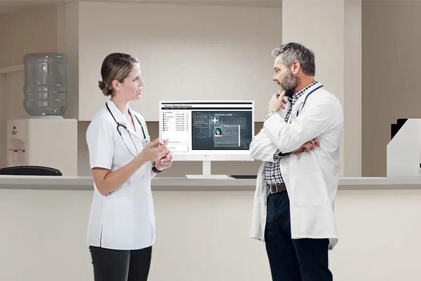 Two doctors standing on either side of an LG all-in-one cloud thin client.