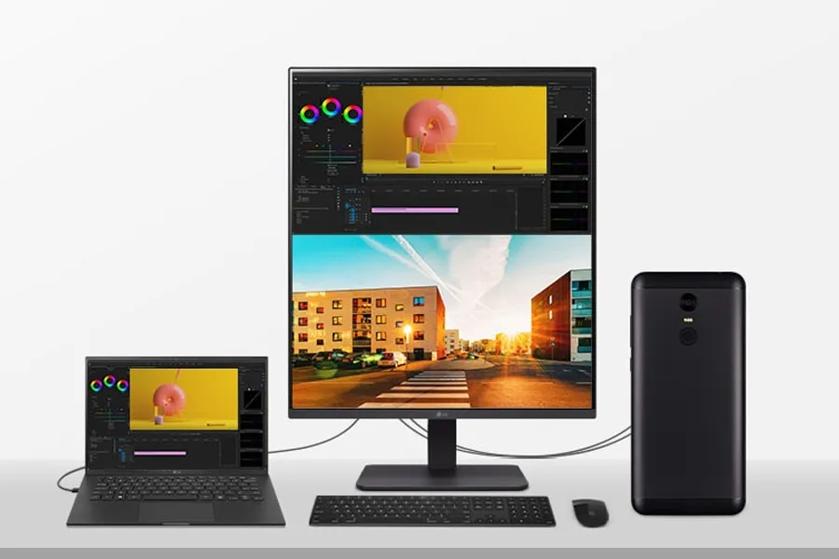 Workspace with a laptop, large monitor, and smartphone on a desk.