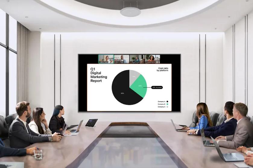 Businesspeople in sleek conference room look at LG display showing business presentation and video call. 