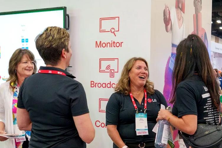 Several ISTE attendees chat with LG employees at the LG booth. Everyone is smiling or laughing. 