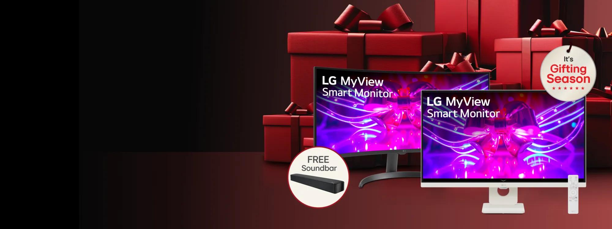 “It’s Gifting Season” badge. A pair of black and white LG MyView smart monitors appear in front of a graphic of a group of red gift boxes. A pop-out of image for a “free soundbar” appears next to the monitors.