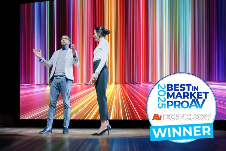 A pair of presenters stand on a darkened stage. Behind them, LG MAGNIT MicroLED creates a dynamic backdrop full of neon lights. A blue and white graphic for AV Technology's 2025 Best in Market Pro AV Award Winner is in the bottom right corner.