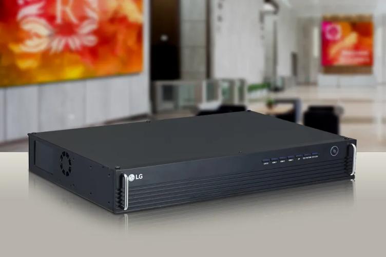 DVLED Controller sits on a reflective beige surface. In the background is a lobby with large, brightly colored Direct View LED displays.