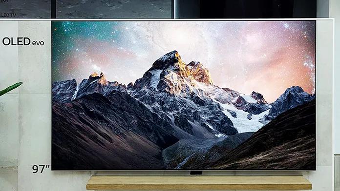 Ultra-high-definition TV showing a dramatic mountain landscape under a colorful sky, viewed close-up.