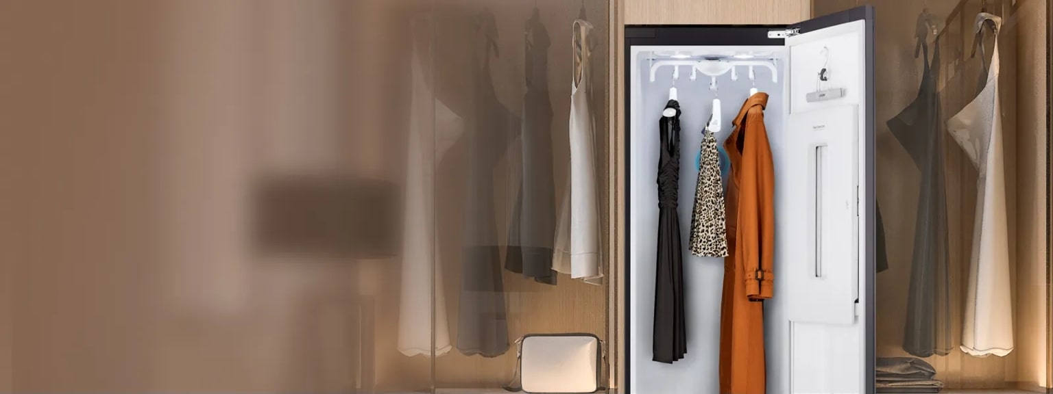 An open LG Styler with various garments hanging inside. A closet setting appears faded in the background. 