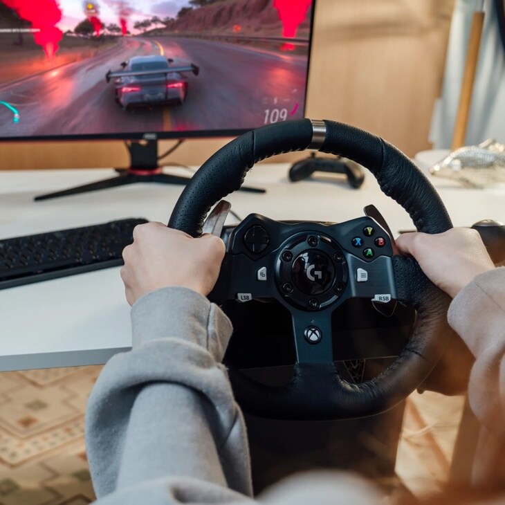 Logitech 941000121 racing wheel controller with leather grip being used for gaming with racing simulation displayed on monitor