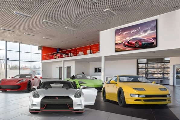 Showroom with red, silver, green, and yellow sports cars and a digital sign reading "Empowerment."