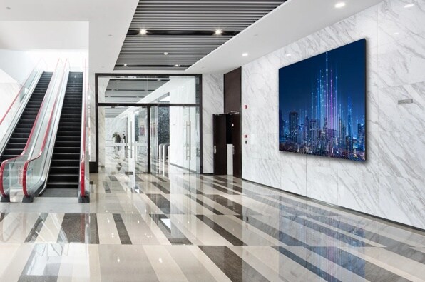 Sleek building lobby with escalator, polished striped floor, and large digital cityscape display.