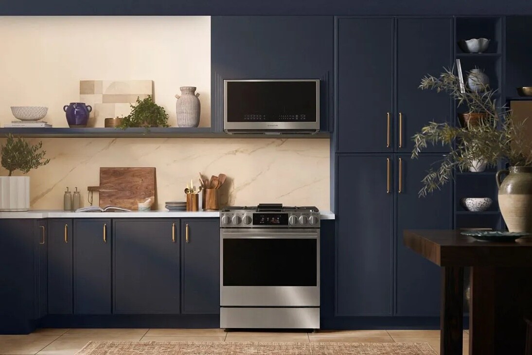 MHEU1738X Over-the-Range Microwave installed in modern navy blue kitchen with marble backsplash, stainless steel range, and decorative vases - Lifestyle View