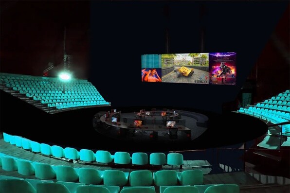 A dimly lit esports arena with teal seating and a central gaming area under a large screen displaying a video game.