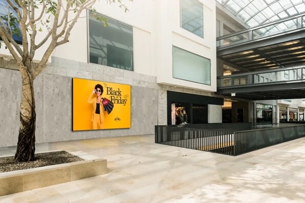 Mall interior with a Black Friday advertisement showing a person in a yellow suit holding shopping bags.