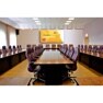 A large conference room with a long wooden table, leather chairs, and a presentation screen at the far end.