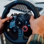 PlayStation 941000110 racing wheel controller with leather-wrapped steering wheel, blue accent buttons, and red dial being held in gaming position