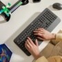 Logitech 920010908 wireless keyboard with hands typing on white desk alongside mouse and colorful paper clips