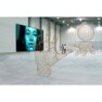 A spacious room with wireframe sculptures of hands and a sphere, and a digital screen showing a blue-toned face.