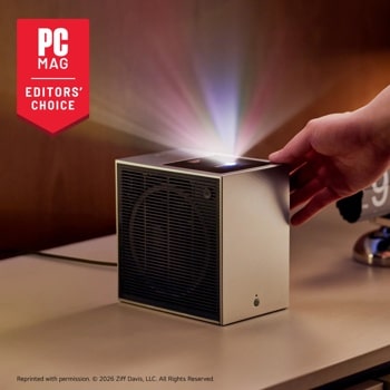 PU615U Projector with PC Mag Editors Choice award badge displaying colorful light beam projection while hand adjusts the compact cube design