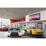 Showroom with red, silver, green, and yellow sports cars and a digital sign reading "Empowerment."