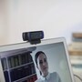 Logitech webcam 960001401 mounted on laptop monitor with blue LED indicators during video call
