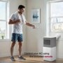 LG Portable Air Conditioner with person using remote control in bright apartment with city view through windows - Control your AC using the included remote
