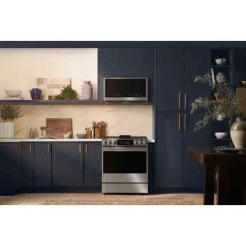MHEU1738X Over-the-Range Microwave installed in modern navy blue kitchen with marble backsplash, stainless steel range, and decorative vases - Lifestyle View