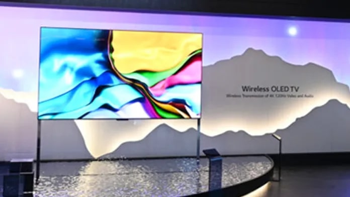 Vibrant OLED TV in a showroom with a glowing ceiling fixture and a mountain-shaped backlit display wall.