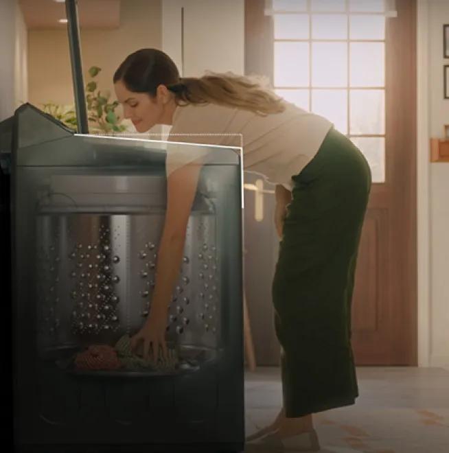 A woman reaching into a washer with the EasyUnload feature.