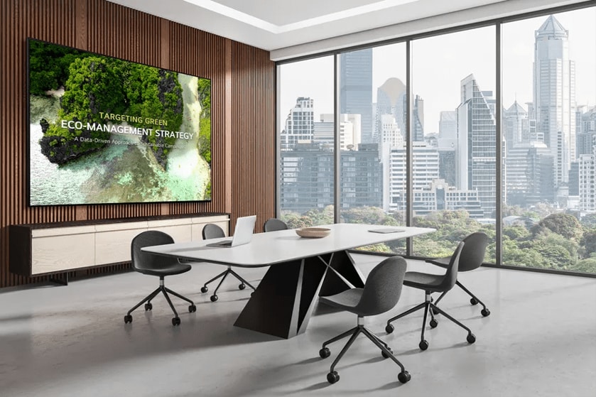 Modern conference room with a large screen and city skyline view through windows.