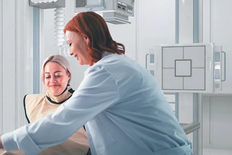A doctor adjusts a patient's x-ray protective smock. An LG Digital X-Ray Detector is behind them, ready to be operated.