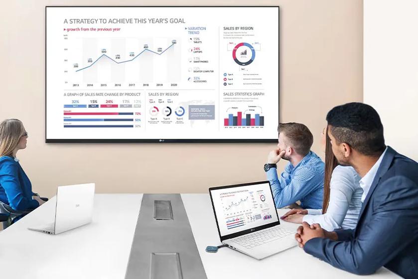 A businessman in a conference room screenshares a presentation to the large LG digital signage using his LG laptop and One:Quick Share.