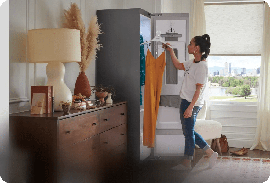A woman places a delicate dress on a hanger inside of the LG Styler®.
