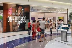 Shoppers walk past an LG video wall in a busy shopping mall. 