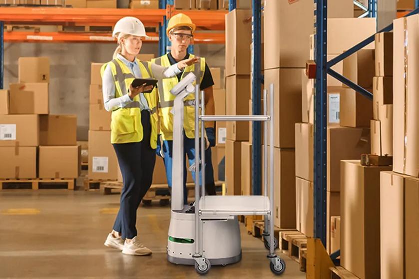 CLOi assists two workers in a large warehouse.