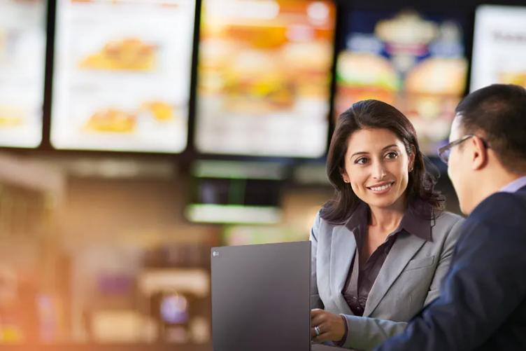 An LG Saleswoman shows a quick-serve restaurant manager something on her LG gram in a franchise restaurant. 