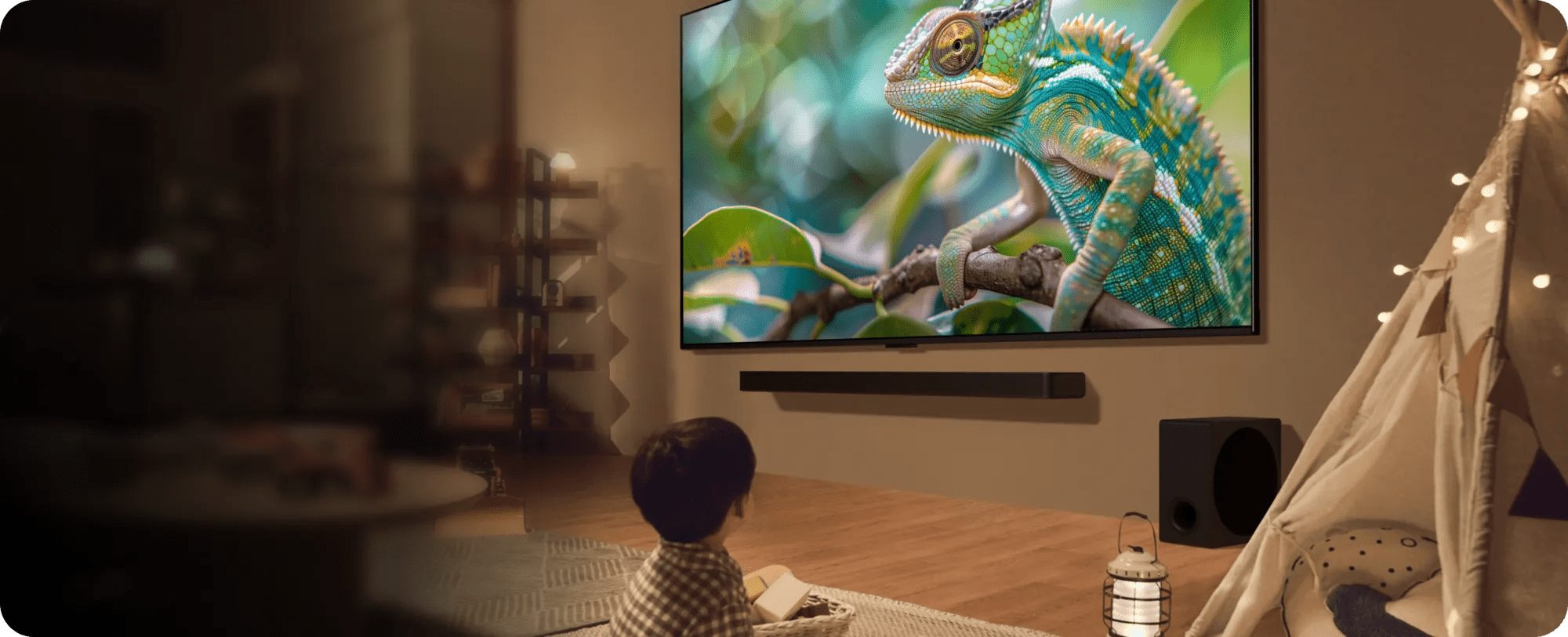 A child sits on the floor, captivated by a movie playing on the television in a cozy living room setting.