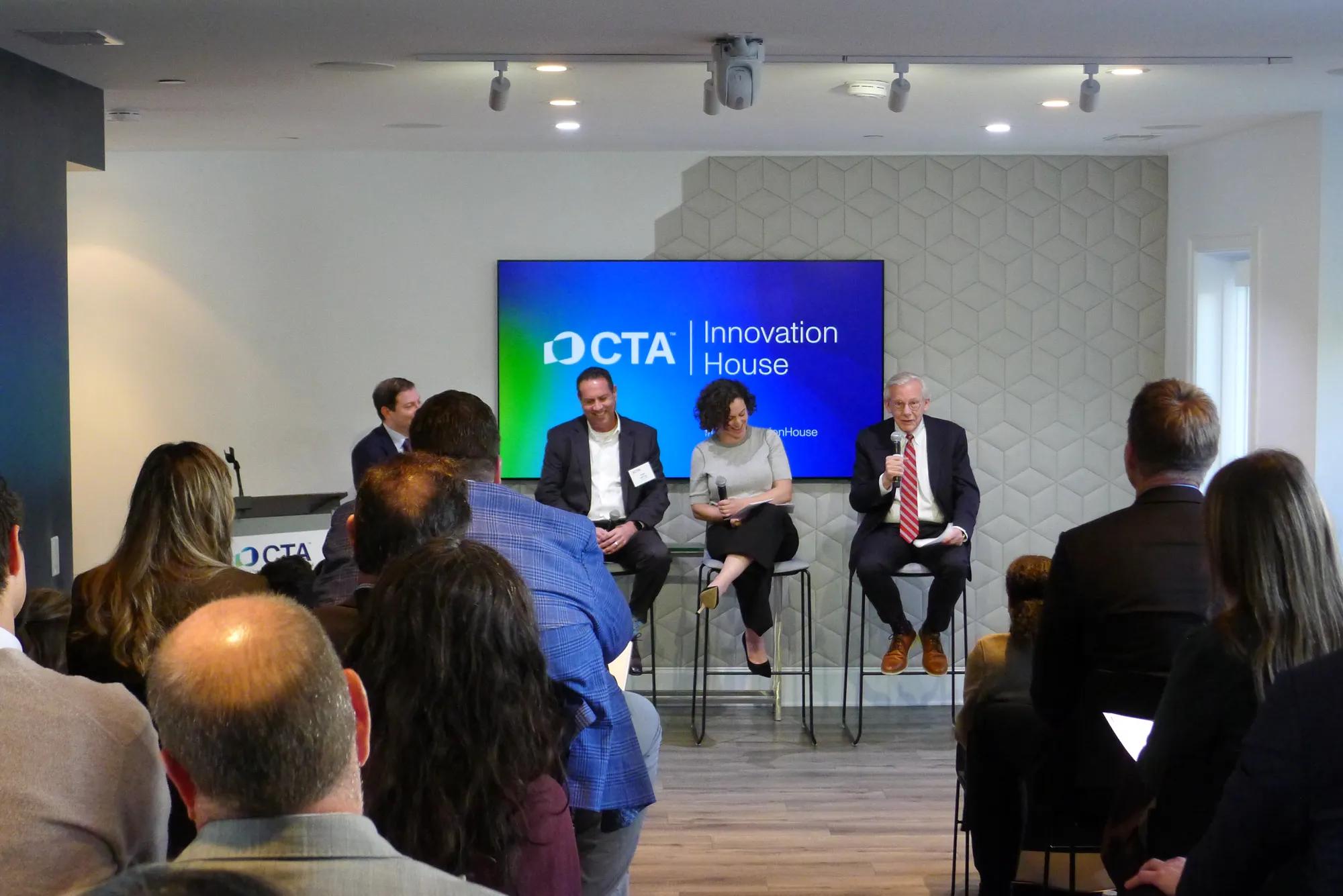 An audience watches a panel of three speakers and a moderator in front of a “CTA Innovation House” screen.