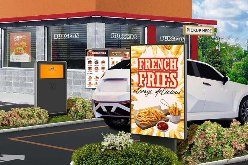 Drive-thru with a white car and signs for French fries and order pick-up.