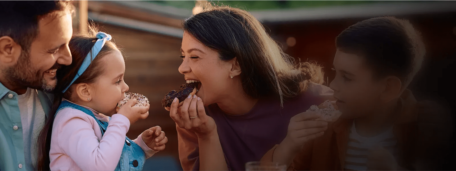 A smiling young family shares frosted donut treats.
