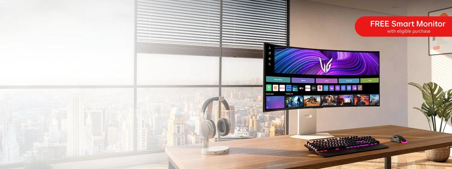 A widescreen monitor on a desk within an office. “Free smart monitor with eligible purchase” text above.