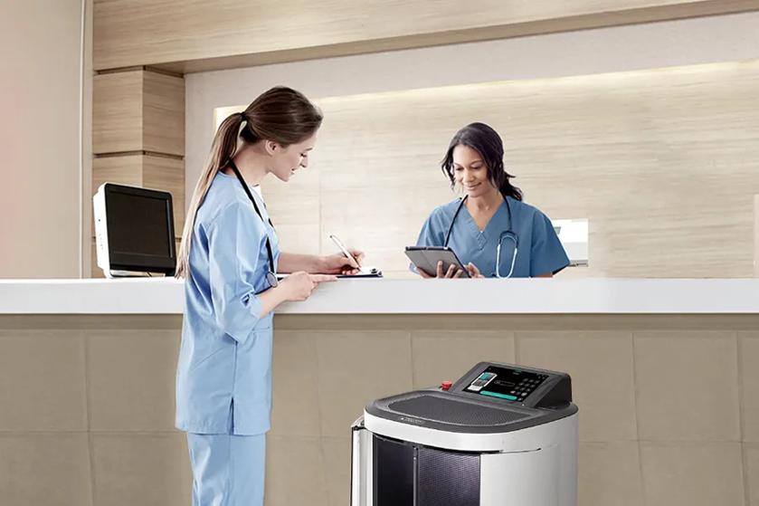 CLOi ServeBot is next to a nurse talking with a receptionist.